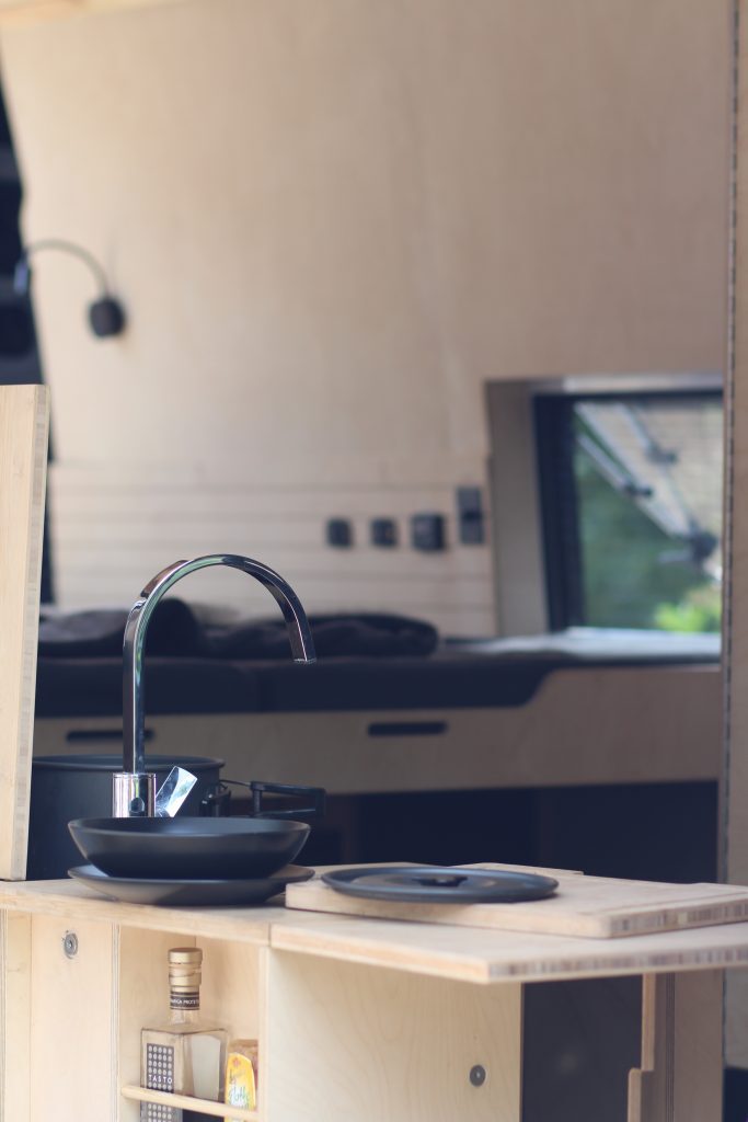 Im Innenraum des Wohnmobils treffen rustikale Holzmöbel auf schwarz Farbtöne.